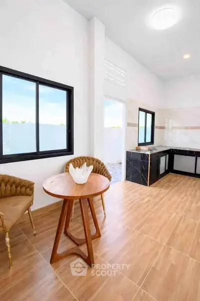 Modern kitchen with open layout and stylish dining area, featuring elegant chairs and a wooden table.
