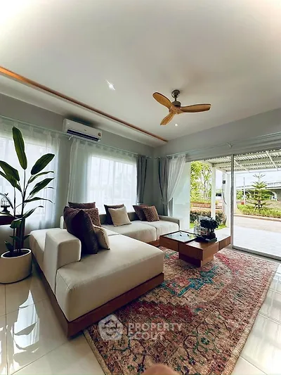 Spacious living room with modern decor, large windows, and garden view, perfect for relaxation and entertaining.