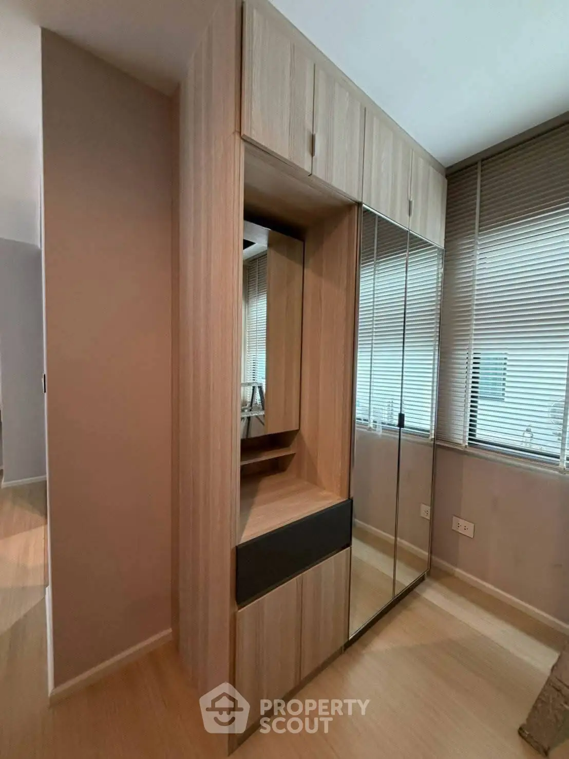 Modern bedroom with sleek built-in wardrobe and large mirror reflecting natural light.
