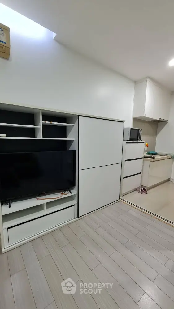 Modern minimalist living room with sleek storage and open kitchen layout