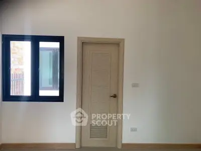 Minimalist interior room with window and wooden door, ideal for customization.