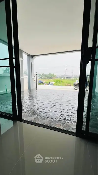 Spacious covered patio with sliding glass doors and scenic outdoor view, perfect for relaxation.