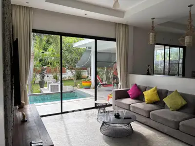 Spacious living room with pool view and modern decor, perfect for relaxation and entertaining.
