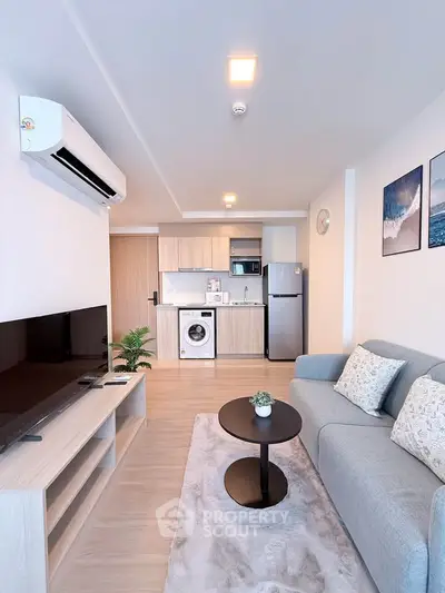 Modern living room with open kitchen, featuring sleek appliances and stylish decor.