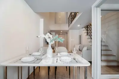 Modern duplex dining area with elegant table setting and staircase view