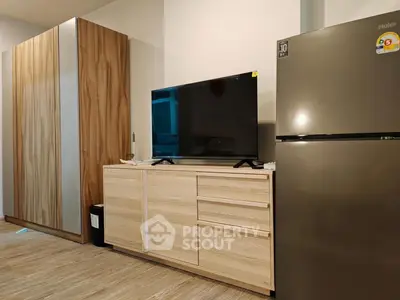 Modern living room with sleek TV stand and refrigerator, showcasing contemporary interior design.