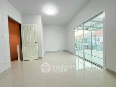 Spacious living room with sliding glass doors leading to a balcony, featuring modern tile flooring.