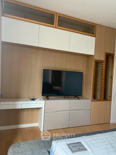 Modern living room with built-in wooden entertainment unit and flat-screen TV.
