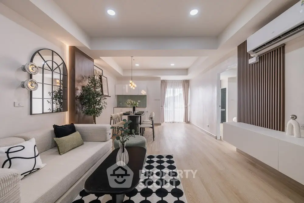 Spacious modern living room with elegant decor and open dining area, featuring stylish lighting and cozy ambiance.