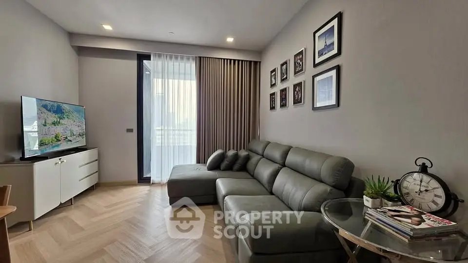 Modern living room with sleek leather sofa and wall art, featuring a large TV and stylish decor.