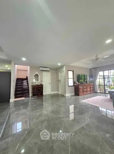 Spacious modern living room with marble flooring and ample natural light, featuring elegant decor and open layout.