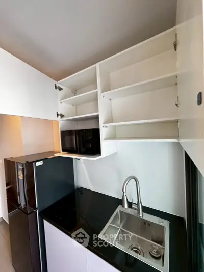 Modern kitchen with sleek black countertop and built-in microwave, featuring ample cabinet storage.