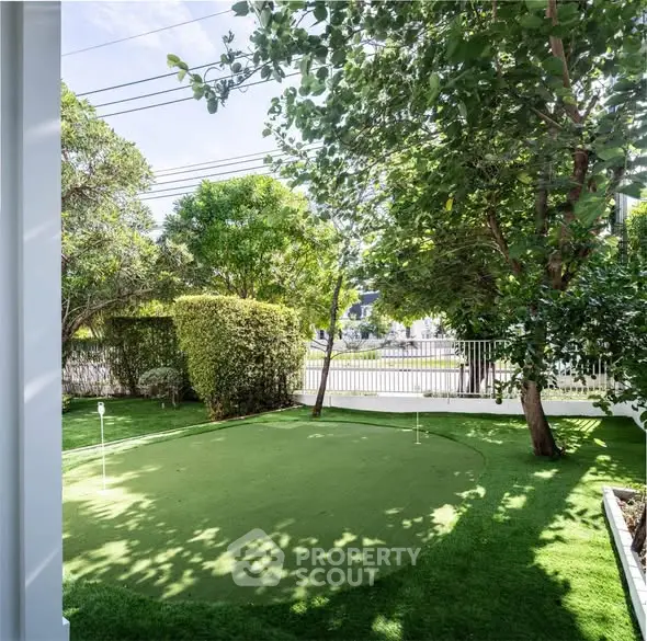 Charming backyard with lush greenery and private putting green, perfect for golf enthusiasts.