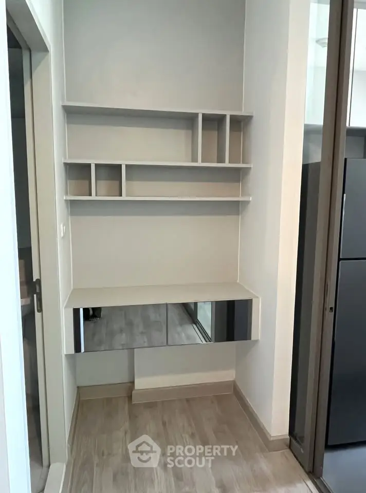 Modern minimalist study nook with sleek shelving and mirrored desk in stylish apartment.