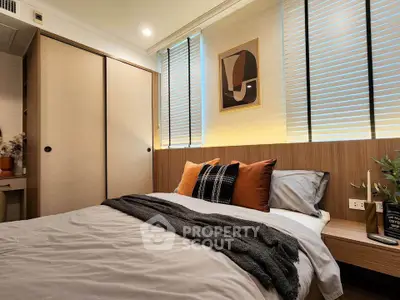 Cozy bedroom with modern decor and ample natural light, featuring a stylish bed and built-in wardrobe.