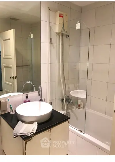 Modern bathroom with sleek fixtures and a glass-enclosed bathtub in a stylish apartment.