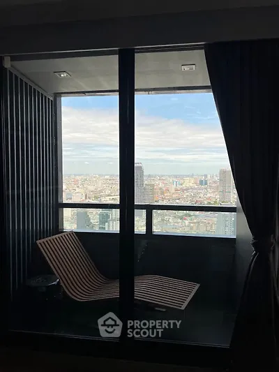 Stunning high-rise balcony with panoramic city view and modern lounge chair.