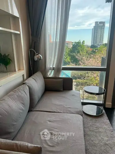 Stylish living room with cozy sofa and stunning city view through large window.
