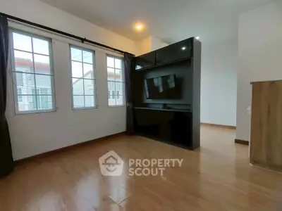 Spacious living room with modern TV setup and large windows