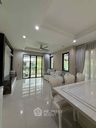 Elegant living room with modern decor and large windows opening to a balcony with a view.