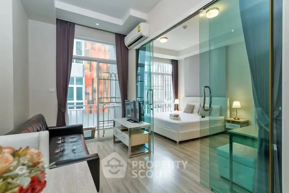 Modern studio apartment with glass partition, cozy living area, and stylish decor.