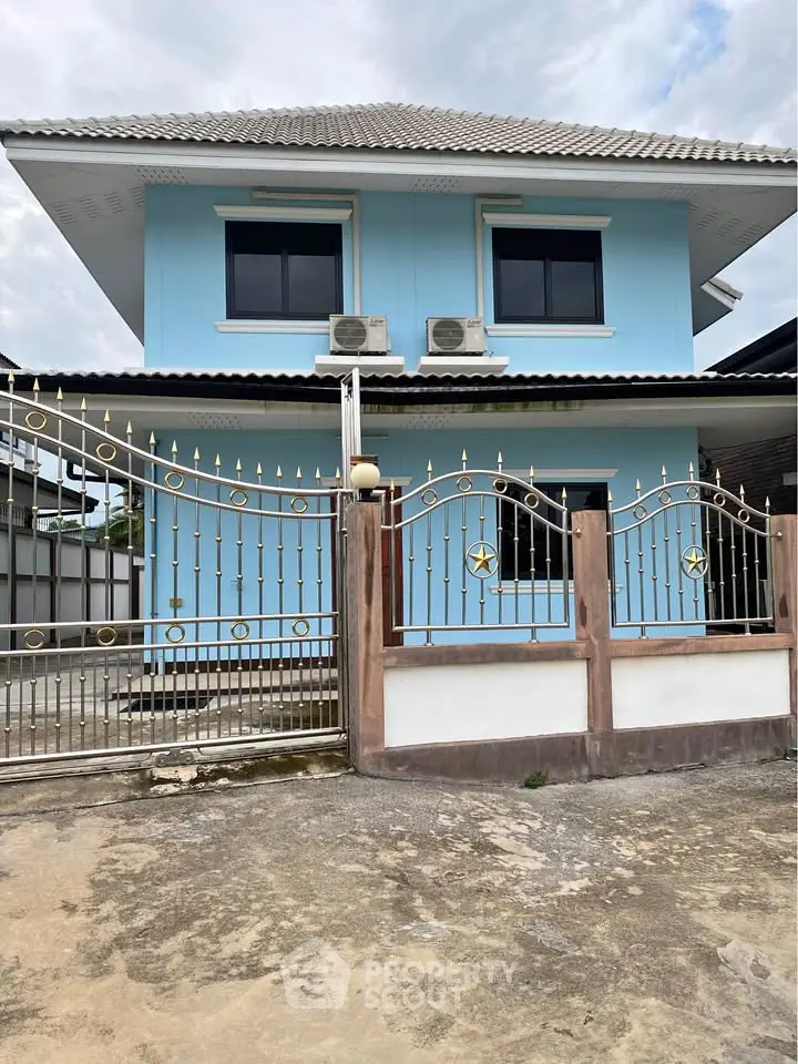 Charming two-story blue house with decorative gate and spacious driveway, perfect for family living.