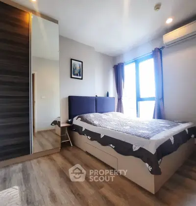 Modern bedroom with large window and stylish decor in a contemporary apartment.