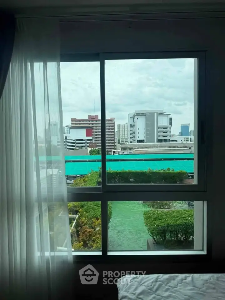 Bright window view from a modern apartment overlooking cityscape and greenery.
