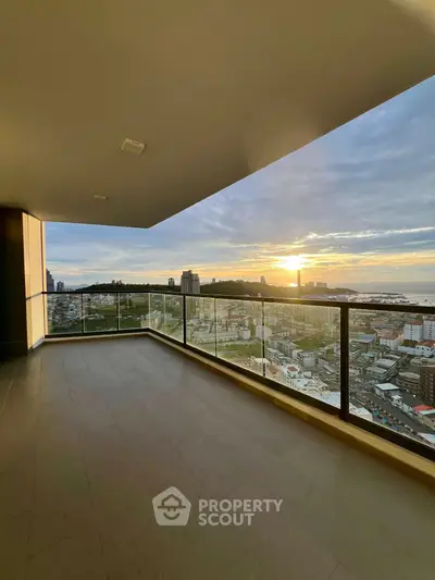 Stunning high-rise balcony with panoramic city and ocean views at sunset.