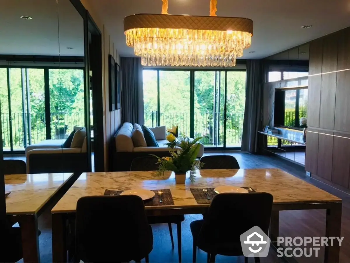 Luxurious modern living room with elegant chandelier and large windows offering stunning garden views.