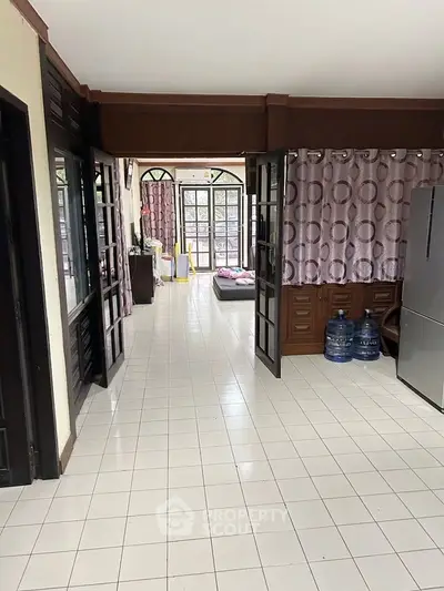 Spacious living area with tiled flooring and large windows for natural light.