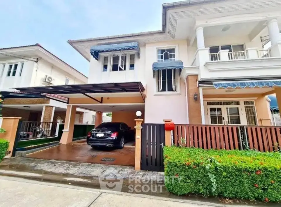 Charming two-story house with carport and lush greenery in a serene neighborhood.