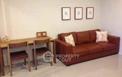 Cozy living room with brown leather sofa and wooden dining set