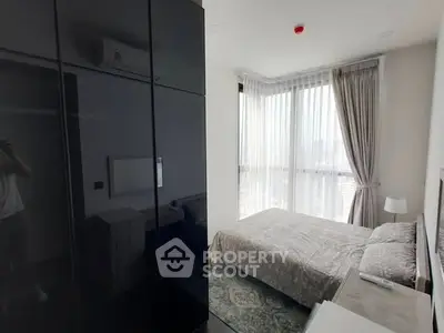 Bright bedroom with large windows and modern furnishings in a high-rise apartment.