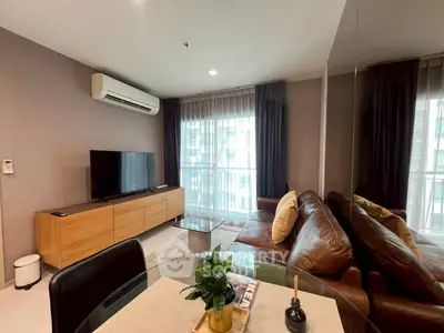 Modern living room with leather sofa, large TV, and stylish decor in a bright apartment.