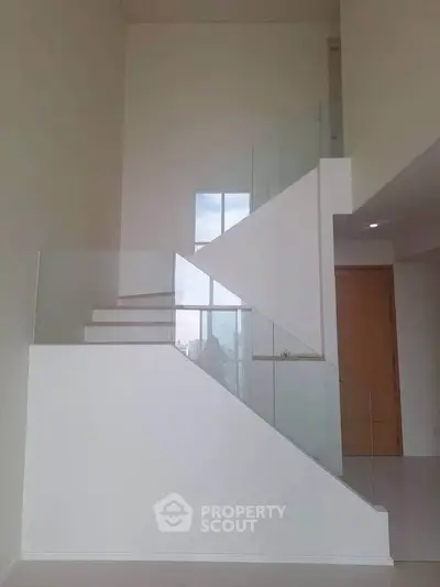 Modern minimalist staircase with glass railing in a bright interior space