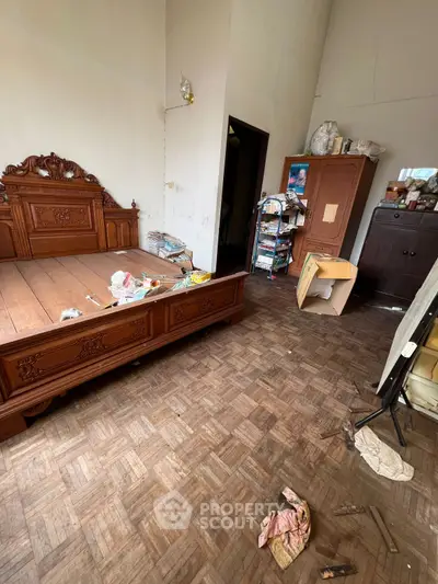 Spacious bedroom with wooden flooring and ornate bed frame, ideal for customization.