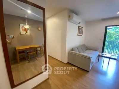 Spacious living room with modern decor and dining area, featuring a cozy sofa and balcony view.