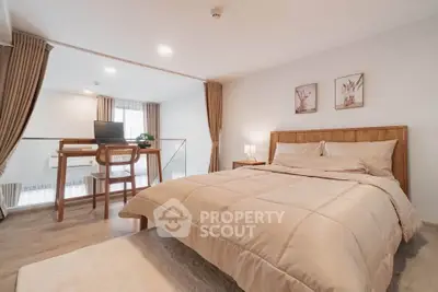 Spacious bedroom with elegant decor and cozy workspace in modern apartment.