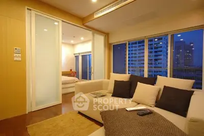 Modern living room with cozy beige sofa and city view, adjacent to a stylish bedroom.