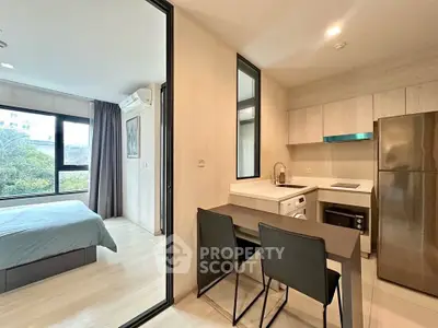 Modern apartment with open kitchen and cozy bedroom, featuring sleek design and natural light.