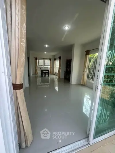 Spacious living room with elegant curtains and glossy tiled floors.
