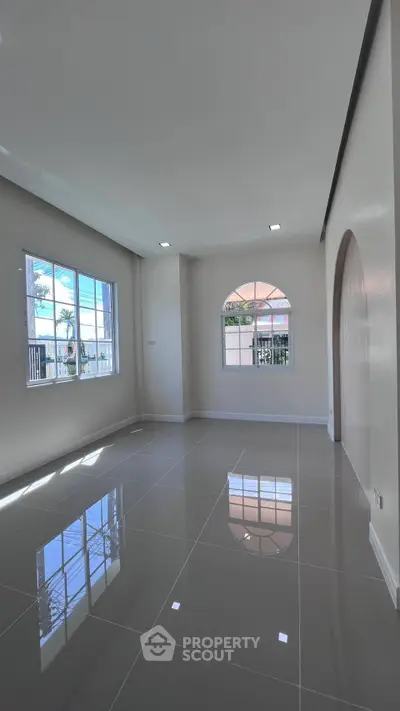 Spacious modern living room with glossy tiled floors and large windows for natural light.