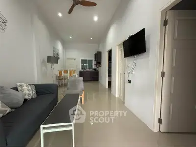 Modern living room with sleek furniture and open layout, featuring a wall-mounted TV and stylish decor.