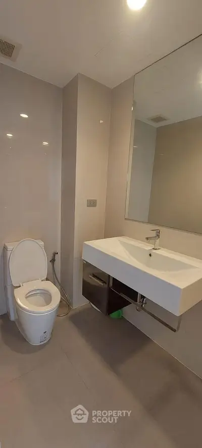 Modern bathroom with sleek fixtures and large mirror in a contemporary home.