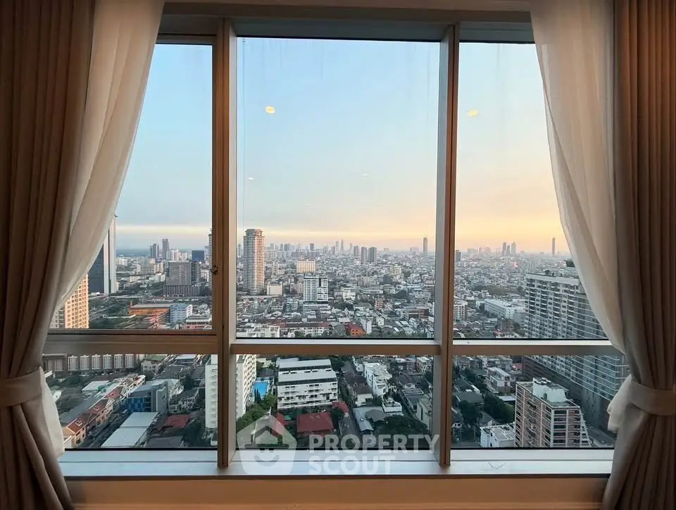 Stunning cityscape view from a high-rise apartment window with elegant curtains framing the skyline.