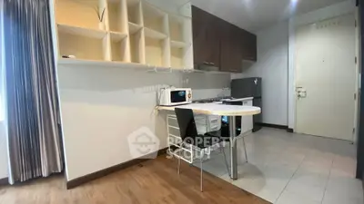 Modern kitchen with open layout, featuring sleek cabinets, dining area, and appliances in a cozy apartment setting.
