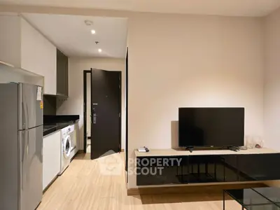 Modern living room with sleek kitchen, featuring TV and appliances in a stylish apartment.