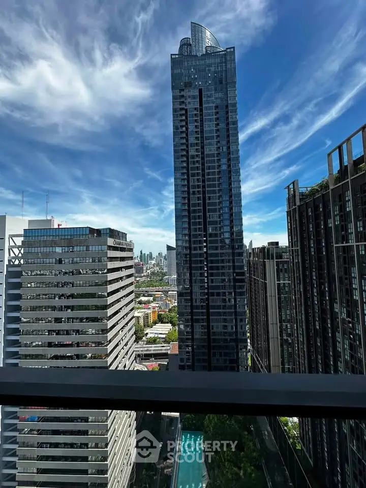 Stunning cityscape view from a high-rise balcony with modern skyscrapers and clear blue sky.