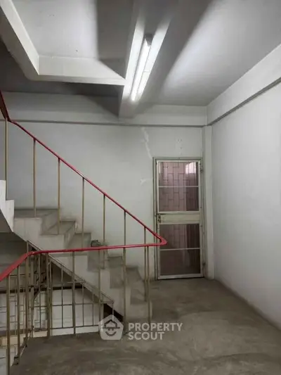 Stairwell with red railing and glass door in minimalist building